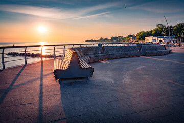Obraz premium Colorful morning seascape of Baltic sea. Splendid summer sunrise on Timmendorfer Strand resort with empty wooden benches, Germany, Europe. Vacation concept background.