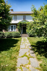 Fototapeta premium Long stone driveway into a house between rows of trees and lawn.