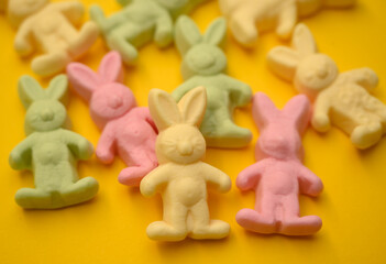 Naklejka premium A collection of pastel bunny-shaped gummy candies on a bright yellow background. Perfect for Easter, holiday decorations, and festive spring-themed designs.