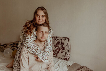 A woman is comfortably seated on a mans back while resting on a bed