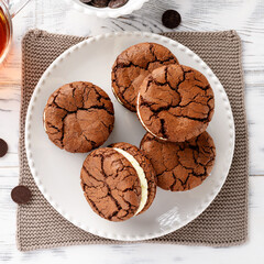Chocolate sandwich cookies, brownie biscuits with cream cheese filling. white wooden table , top view