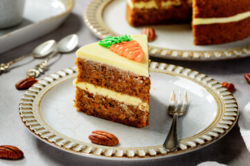 Piece of Carrot layered cake with cream cheese frosting decorated with carrots.
