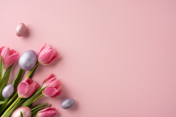 Pink tulips and speckled Easter eggs creatively arranged on a soft pink background