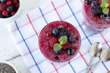 Frozen berry chia seed pudding with fresh mint leaf on kitchen table. Top view. Healthy food, raw...