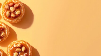 Golden pastries topped with nuts, set against warm orange backgr
