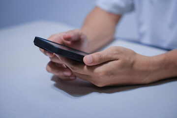 Cropped shot of young businessman hand typing on smartphone or laptop computer while working in office room.