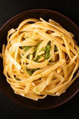 Creamy pasta dish topped with vibrant green pesto and toasted pi