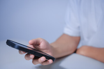 Cropped shot of young businessman hand typing on smartphone or laptop computer while working in office room.