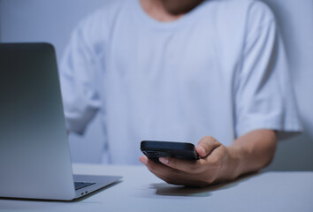 Cropped shot of young businessman hand typing on smartphone or laptop computer while working in office room.