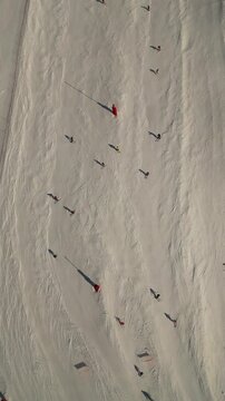 vertical drone flat lay video of skiers and snowboarders running at ski slope in European luxury French ski resort Courchevel in sunny day
