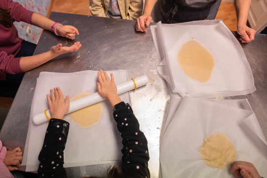 Young girl kneading butter cookies dough during cooking class workshop for children
