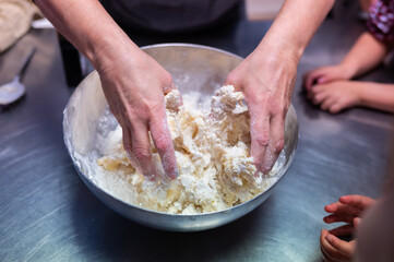 Hands of female chef kneading butter cookies dough during cooking class workshop for children