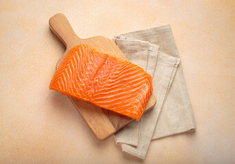 Fresh salmon fillet on wooden board, with linen napkin ready for delicious meal preparation and...