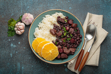 Feijoada, a hearty brazilian stew, with white rice and orange slices, showcasing a vibrant culinary tradition of Brazil alongside garlic and parsley