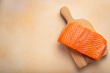 Fresh salmon fillet on wooden board, ready for delicious meal preparation and cooking. Healthy...