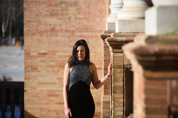 young and beautiful brunette woman in elegant black dress is in the famous square of spain in...