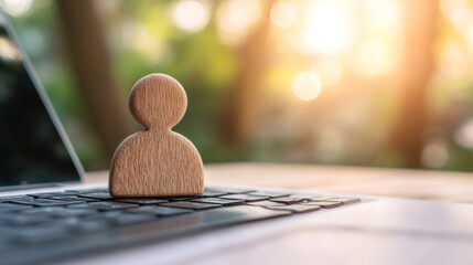 Wooden figure placed on laptop keyboard symbolizing online presence, user profile, or customer service in digital world