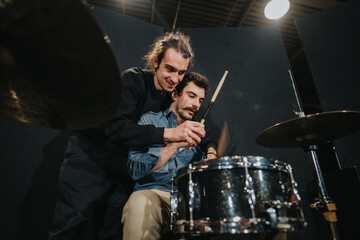 Musicians bonding and practicing drumming skills together on a drum set in a rehearsal setting,...