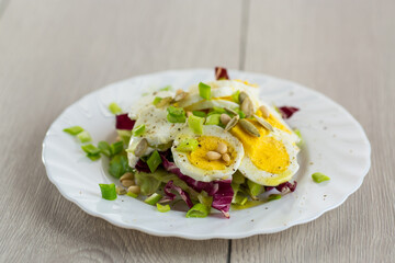 Homemade salad with greens in a plate on a wooden table