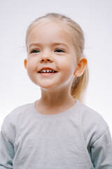 Portrait of a little smiling girl in joyful anticipation on a gray background