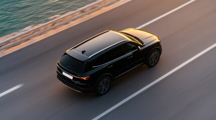Sleek black SUV cruising along coastal road, reflecting sunset h