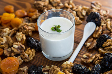natural yogurt with nuts, dried apricots and prunes on a wooden table