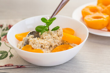 Fragrant oatmeal with tender peaches in a white bowl
