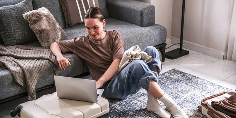 Woman packing suitcase with laptop and credit card.travel planning, online booking, minimalist lifestyle, and solo adventure.modern travel, e-commerce, and digital nomad themes © shintartanya