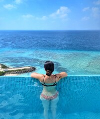 A woman enjoys a stunning infinity pool with a breathtaking view of the turquoise waters in the Maldives