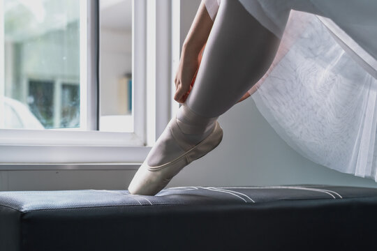 Ballet dancer girl putting on pointe ballet shoes preparing to perform classical ballerina