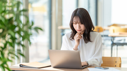 Obraz premium パソコンの画面を見ながら考える女性・ビジネスウーマン