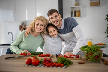 Family cooking together in a bright kitchen while preparing healthy meals with fresh vegetables