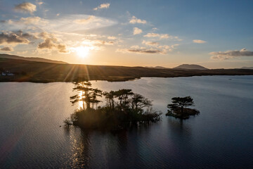 Lough Bofin’s backlit islands glisten, sunlight reflecting off mirror-like waters, Connemara, Ireland