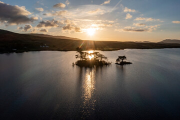 Lough Bofin’s small island at dawn, golden hour glow on peaceful waters, Connemara, Galway, Ireland