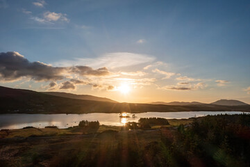 Golden Sunset Over Lough Bofin, Connemara: The sun's rays dance across tranquil waters, illuminating the small island in warm golden light
