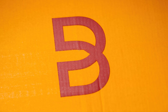 Frankfurt, Germany - Apr 1, 2023: AA close-up of the Breuninger logo printed in red on an orange cardboard box packaging features a visible seam running across the design, creating a split effect.