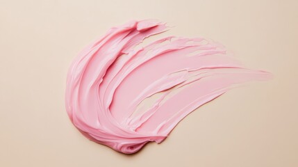 Obraz premium Soft pink cream spread artistically on a smooth beige surface, showcasing beauty and texture in skincare or cosmetic application