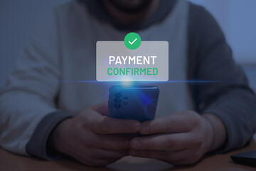 A person using a smartphone with a digital "Payment Confirmed" confirmation message on the screen. Mobile banking and online transactions.