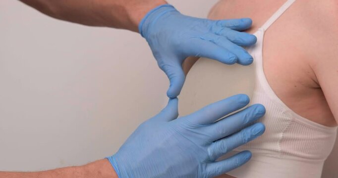 doctor and patient, exam, consultation in clinic office, holding breast enlargement implant in hands, plastic surgery, beauty enhancement, medical Mammoplasty and plastic surgery, mastopexy