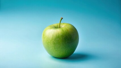A single, vibrant green apple rests on a serene light-blue background, showcasing its smooth skin and subtle textures in a minimalist still life composition.