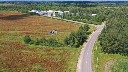 Panoramic view of a typical European countryside in midsummer. Sun-scorched field, asphalt motorway, small villages and factories in the middle of fields and forests