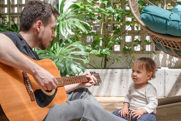 Father playing guitar for his 14-month-old son