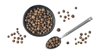 Dried whole allspice berries in bowl ana spoon flying isolated on white background. Aromatic spicy...