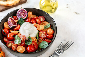 Delicious burrata cheese with fresh tomatoes, spinach, figs and olive oil.