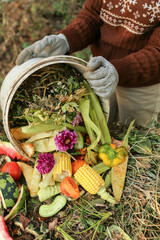 Zero waste, compost. Compost heap pile with bio waste. Farmer hands put weeds grass, flowers,...