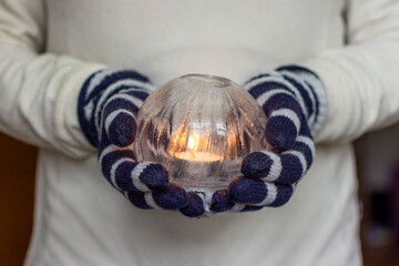 Gloved Hands Holding an Ice Lantern with candle in front of a window.