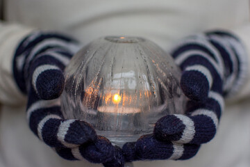 Gloved Hands Holding an Ice Lantern with candle in front of a window.