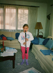 Circa 1995 - 10 year old girl playing the clarinet in a living room. Image is a vintage scan and...