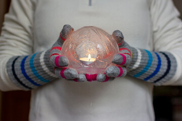 Gloved Hands Holding an Ice Lantern with candle in front of a window.