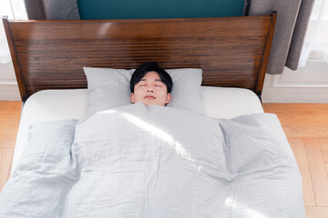 朝日が差し込む中で寝る若い男性